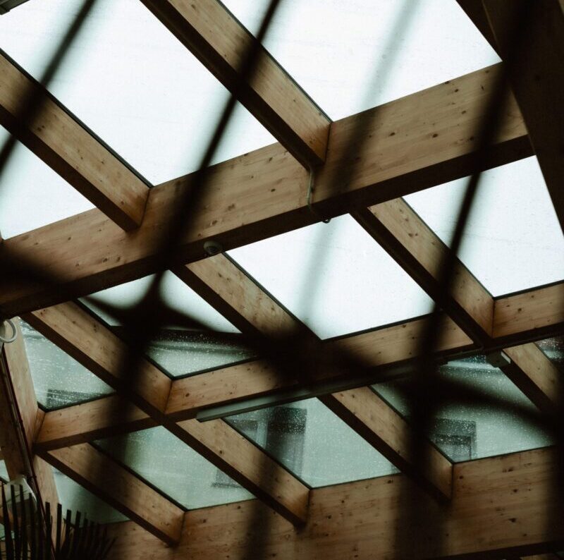A moody and artistic shot of a glass rooftop with a wooden frame, emphasizing geometric patterns.