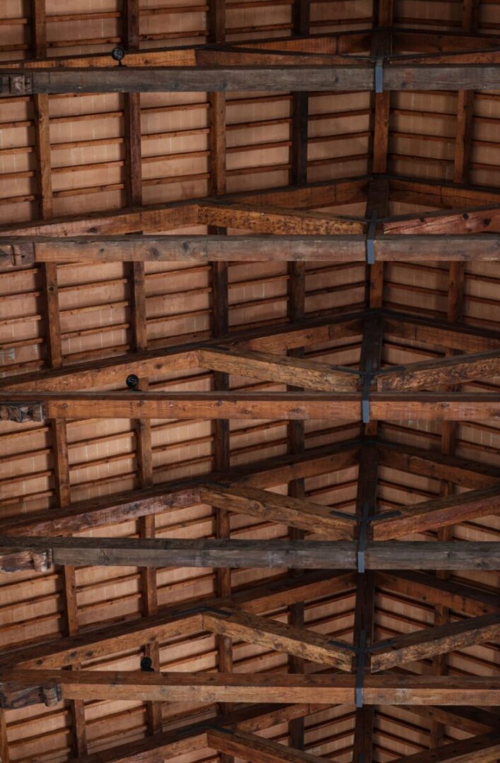 Detailed view of a rustic wooden ceiling with exposed beams, highlighting natural textures.