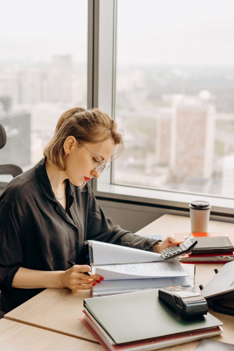 Woman accountant calculating financial documents at office desk.